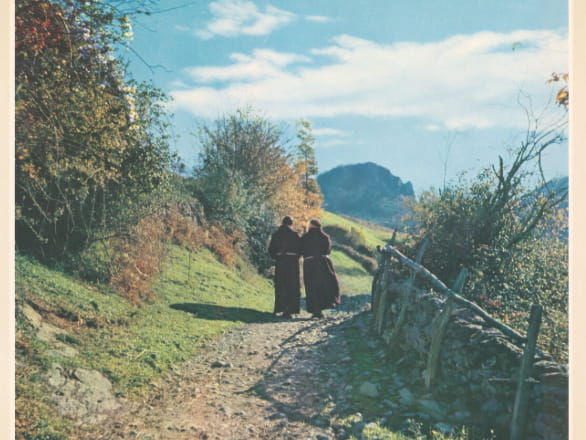 two robed figures walking on trail in the hills