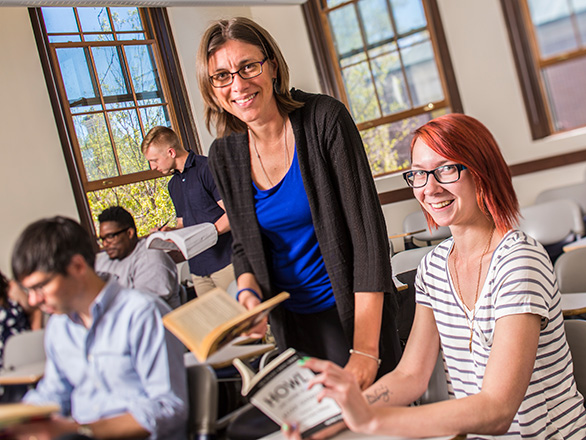 Professor and student review books inside classroom