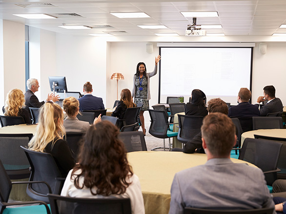 Woman presenting to conference room of people