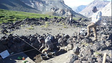 Two people dig in dirt at anthropology excavation site