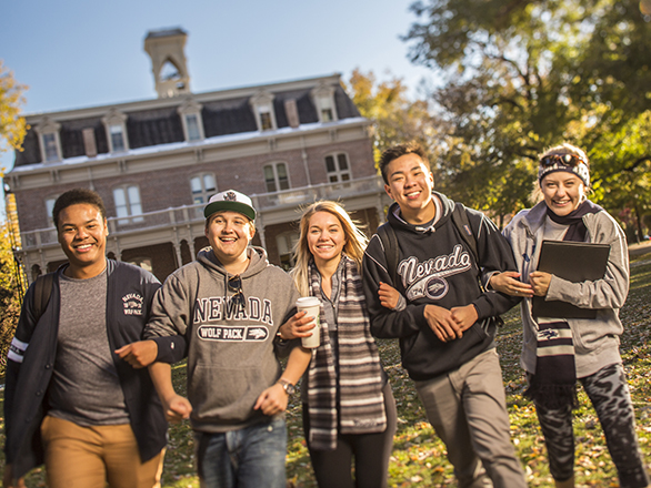 Five students link arms and stand on quad in front of Morrill Hall