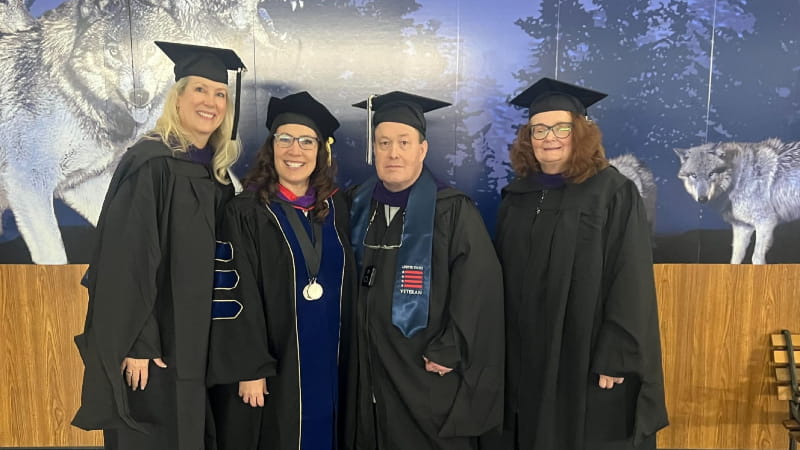 four graduates standing side by side