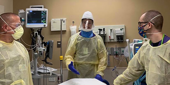 Three doctors wear full PPE in emergency room