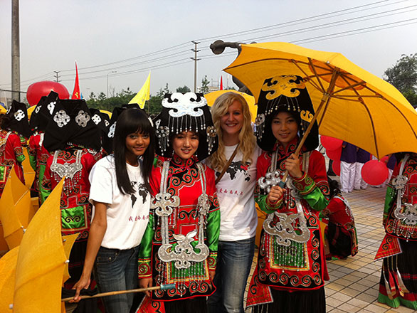 People stand in foreign country wearing cultural regalia and holding an umbrella