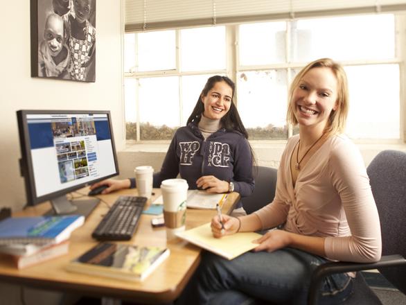 Two people working at a computer and writing together.
