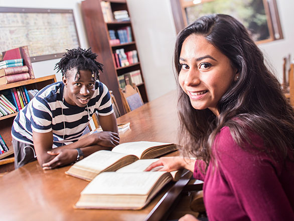Two students looking up from books on table