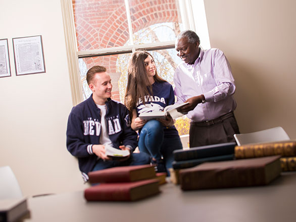 Professor and two students sit in window and look at books