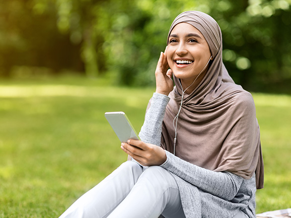 Woman listening to headphones outside on lawn