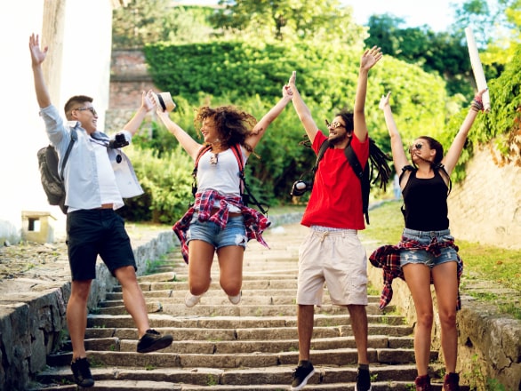 students jumping with staircase and trees in background