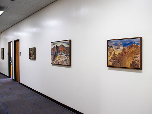 Three paintings of outdoor landscapes hang on an office wall