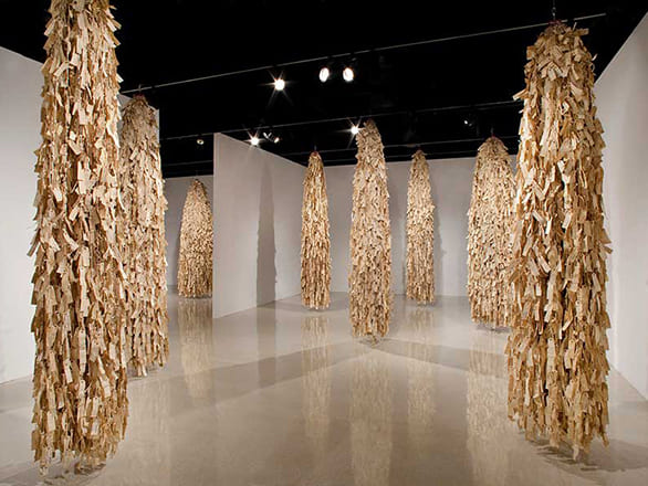 Image of paper strung together and hung from the ceiling against a white background.