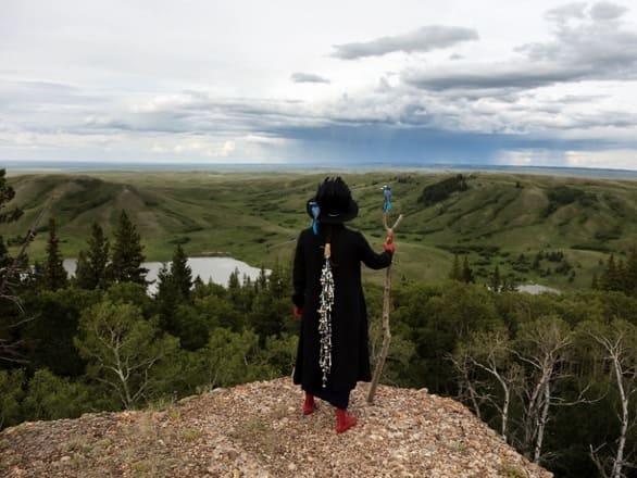 Photo from exhibit of person standing above a mountainous landscape looking out