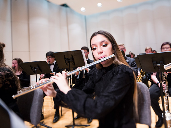 Student playing a flute in an orchestra seating arrangement