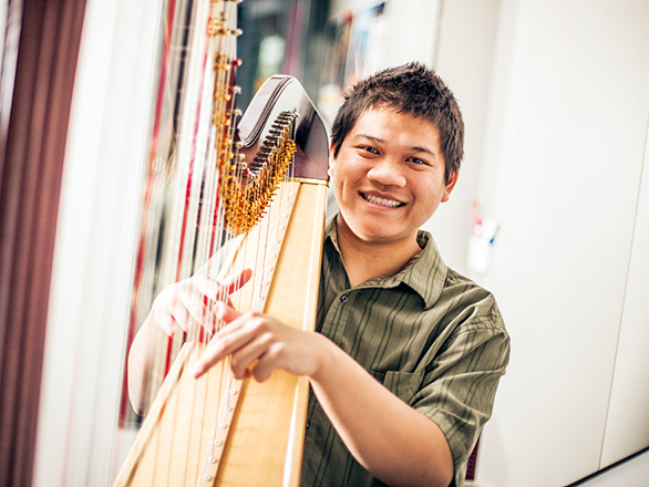 Smiling student playing harp
