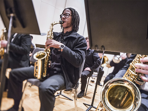 Man playing saxophone with band on stage