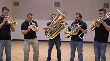 M5 Mexican Brass stands inside room and plays brass instruments