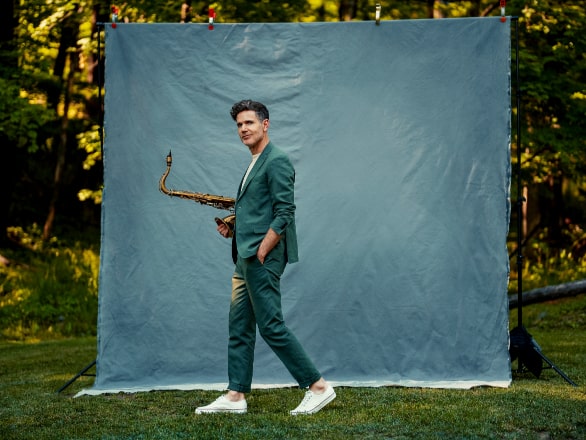 ben wendel holding saxophone standing in front of blue screen