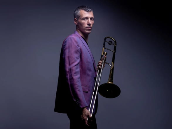 nick finzer in purple suit holding instrument