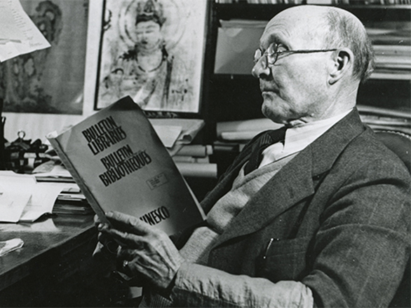 black and white photo of man sitting at desk reading