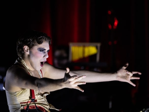 man with hands outstretched while acting on stage