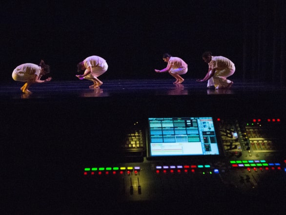mixing board with dancers on stage in background