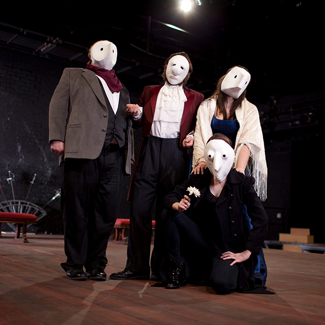 Four actors on stage in masks