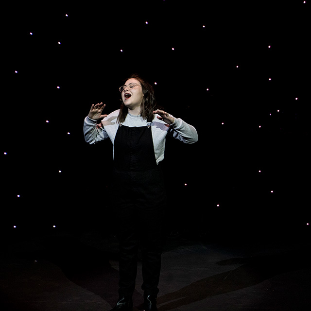 Girl singing on dark stage