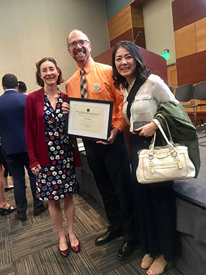 Language faculty stand while holding awards during ceremony