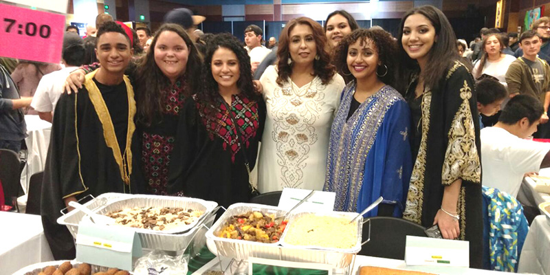 Sinai club members pose in in Middle Eastern dress in front of Middle East food dishes