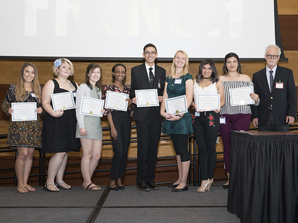 Students stand up on stage with awards