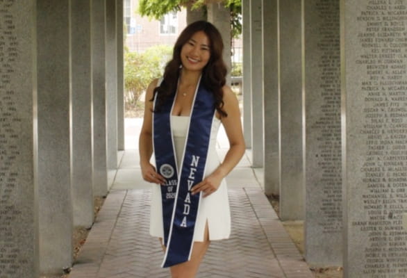 woman smiling with graduation stole in front of pillars