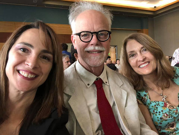 Three professors sit and smile