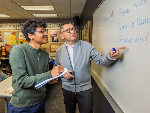 Spanish professor pointing at whiteboard teaching students