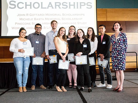 Students stand on stage with scholarship awards