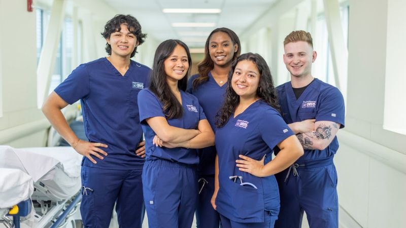 three nursing students practicing skills in a simulation lab