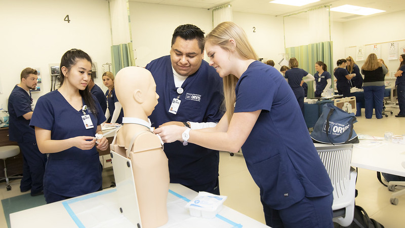 three nursing students practicing skills in a simulation lab