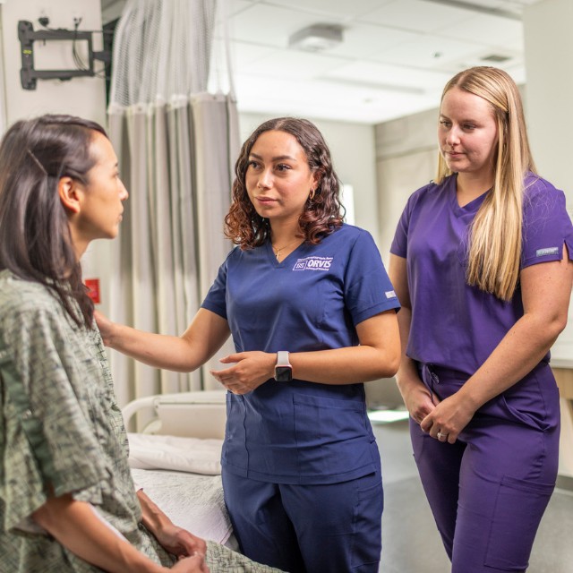 Nursing student, proctor and patient in a hospital room.