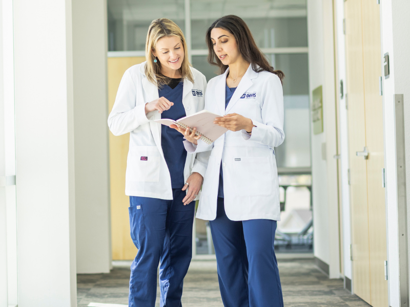 Two nurses looking at a notebook