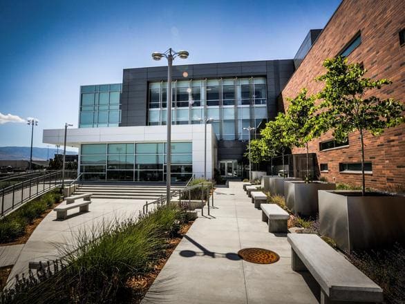 Exterior pathways lines the outside of the Orvis School of Nursing building, a modern facility with alrge glass windows and trees lining the outer facade.