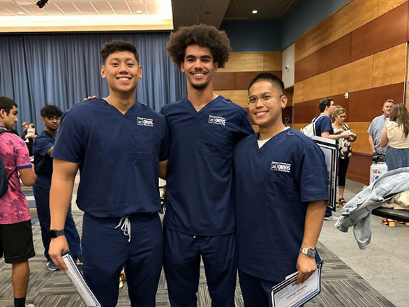 Three OSN Nursing students wearing blue scrubs pose for a photo.