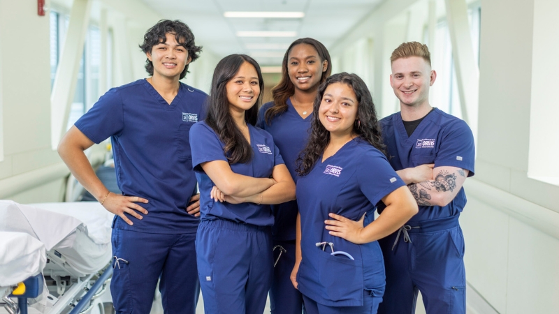 Four Orvis School of Nursing Students poses for a picture while wearing nursing scrubs and stethoscopes. 