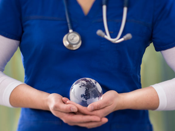 A torso clad in scrubs with arms in front holding a small, glass globe. A stethoscope is visible around the neck of the person.