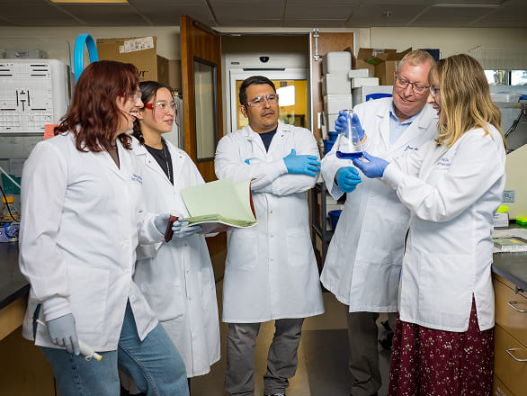 A group of researchers consulting with each other in the lab