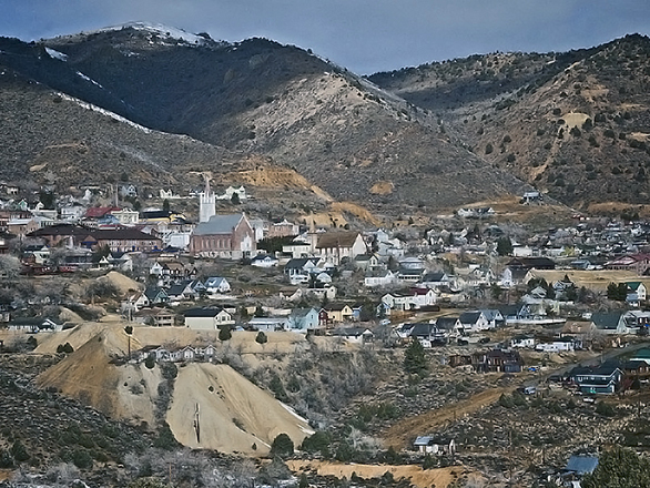 A distant view of Virginia City, nestled into the mountainsides, with buildings and houses scattered throughout the mountainside.