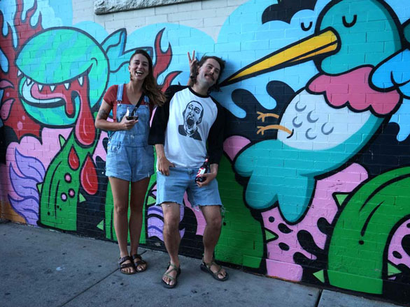 Anna Tatarko and Chris Haslch in front of a graffitied wall
