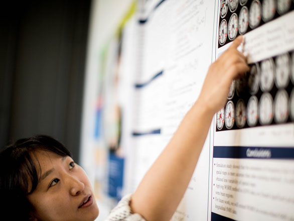 Woman pointing to graphs on poster.