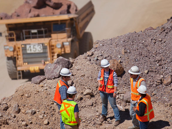 Group of people stand at the edge of a mine site.