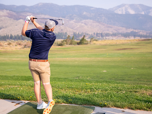 Golfer staring into the distance at ball on driving range