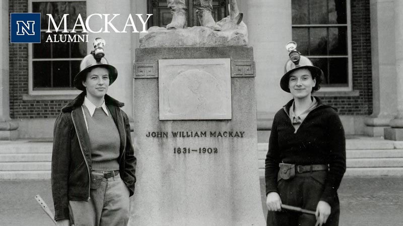 Old photo of two female miners standing in front of Mackay statue.