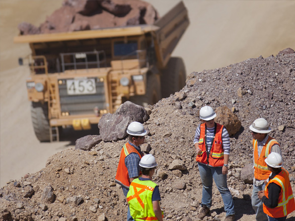 Students and adults wearing safety gear at the edge of a pit mine